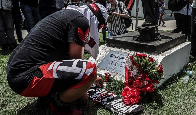 Un aficionado pone flores en homenaje a las víctimas del incendio registrado ayer. EFE