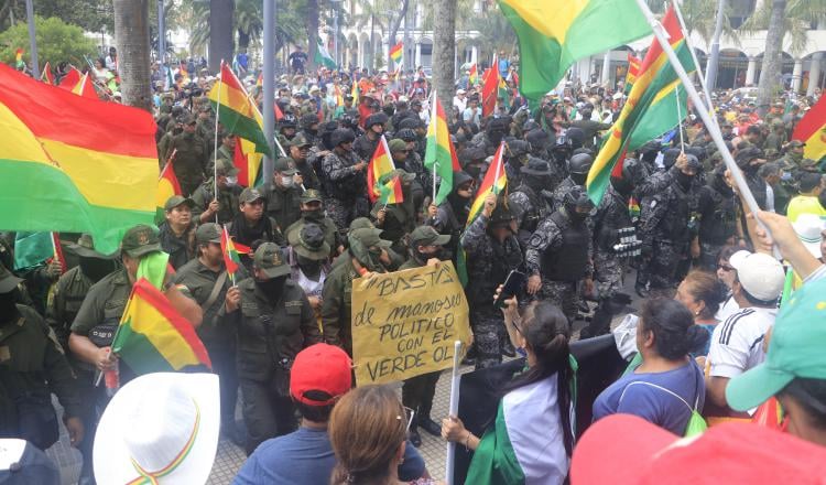 Un grupo de policías ondea la bandera tricolor de Bolivia mientras se repliega a una comisaría. FOTO/EFE