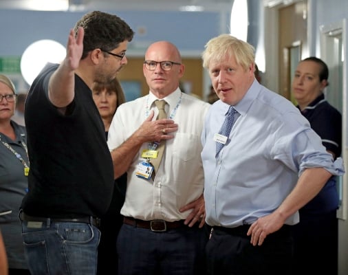 Omar Salem, cuya hija está siendo tratada, en el pabellón de niños Acorn, hace gestos mientras habla con el primer ministro británico, Boris Johnson, durante su visita al Hospital Universitario Whipps Cross en Leytonstone, este de Londres. FOTO/AP