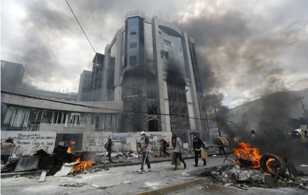 Manifestantes tras una barricada de piedras que bloquea una calle este sábado, en Quito. Foto: EFE.