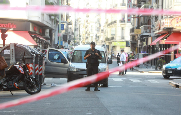 Un agente custodia el vehículo en el que intentaron huir los atracadores de una joyería luego de un tiroteo en la céntrica Avenida Corrientes. FOTO/EFE