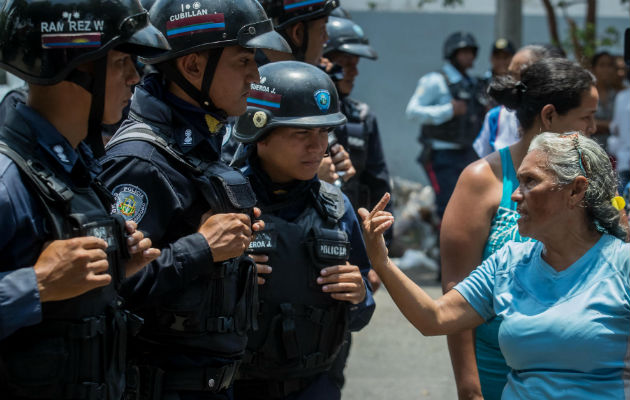 Un grupo de familiares de presos protesta ante miembros de la Policía en las inmediaciones del centro de reclusión de la Policía Estatal de Carabobo. FOTO/EFE 