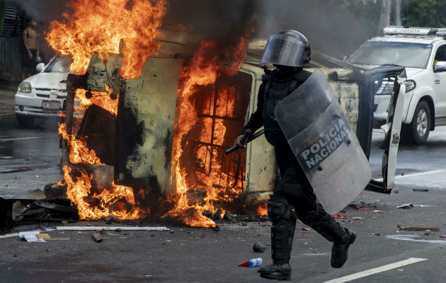 Manifestantes antigubernamentales quemaron el coche policial. Foto: EFE.