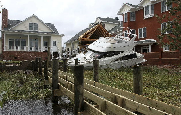 Un bote sin ataduras se sienta detrás de una casa y edificio de condominio en East Front Street después de que fue removido de su muelle por Florence. AP