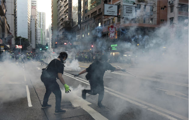 Un hombre afectado por gas pimienta camina ante policías antidisturbios. Foto: EFE.