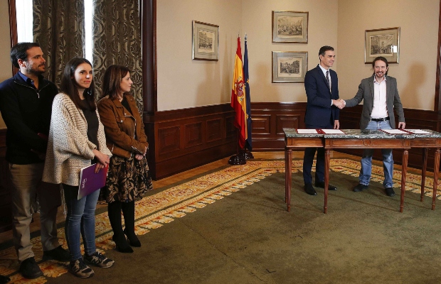 El presidente del Gobierno español en funciones, el socialista Pedro Sánchez (c), y el líder de Unidas Podemos, Pablo Iglesias,d se estrechan las manos tras llegar a un acuerdo para la formación de un Ejecutivo. FOTO/EFE