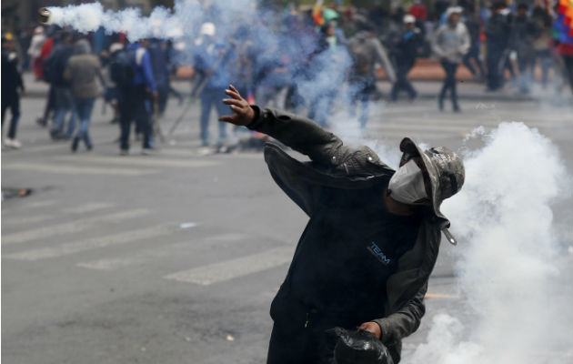 Un simpatizante el expresidente Evo Morales devuelve una lagrimógena a los antimotines. Foto: AP