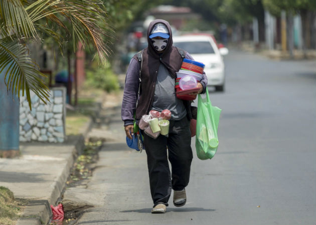 Un vendedor ambulante camina con mascarilla de protección en Managua. Fotos: EFE.