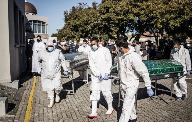 Enterradores cargan ataúdes tras un funeral para víctimas de coronavirus en Ciudad del Cabo en junio. La asistencia a funerales se limita a 50 personas. Foto / Marco Longari/Agence France-Presse — Getty Images.