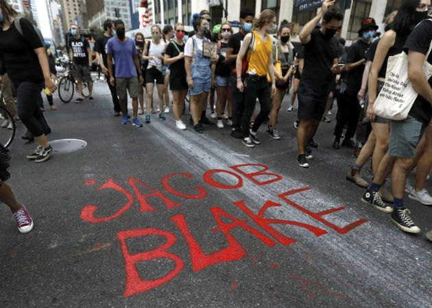 Los manifestantes escribieron en la calle el nombre del afroamericano baleado. Fotos: EFE.