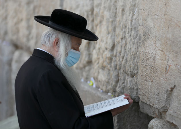 Judíos ortodoxos oran en el muro al oeste de la vieja ciudad de Jerusalén, a dos días de reiniciar el aislamiento total por el coronavirus. EFE.