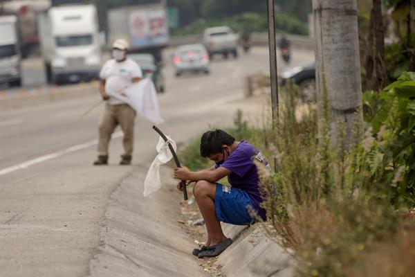 Un niño ondea una bandera blanca en la carretera pidiendo ayuda por hambre debido a la crisis economica provocada por el coronavirus, en Guatemala. EFE