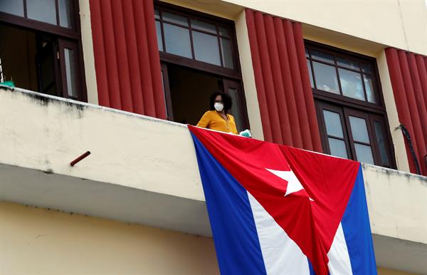 Una mujer sale al balcón donde se expone una bandera cubana, en La Habana, Cuba. EFE