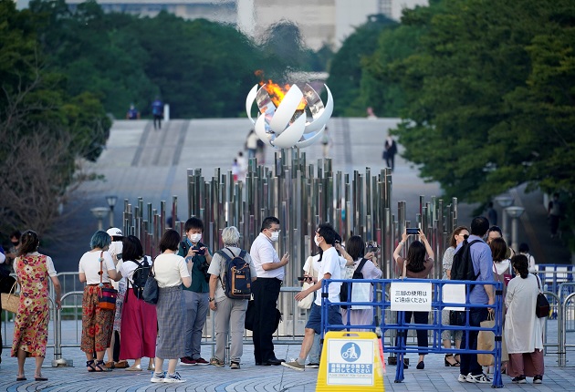 Personas se toman fotos con la Llama Olímpica en Tokio, Japón, que hoy registró nuevo récord de casos diarios de covid-19. Foto: EFE