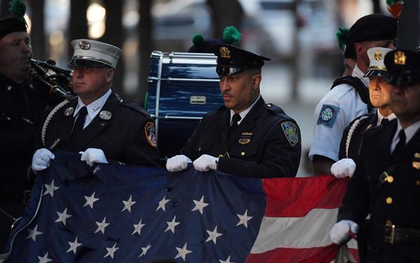 Policías y bomberos de Nueva York sostienen la bandera de Estados Unidos durante el himno nacional en una ceremonia de conmemoración de los atentados del 11S en el World Trade Center, en Nueva York (EE.UU.), este 11 de septiembre de 2021. Foto: EFE