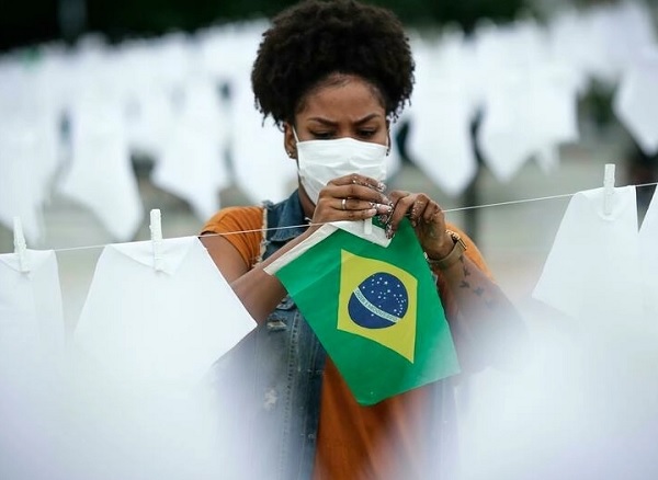 Una voluntaria ayuda a colgar pañuelos blancos durante un homenaje a las miles de víctimas mortales de covid-19 en Río de Janeiro, Brasil, el 8 de octubre de 2021. Foto: EFE