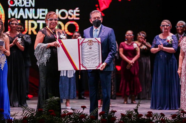 La docente Herminia Gómez Castillo,  representante de la Escuela Oficial Bilingüe Simeón Conte, recibe el pergamino por parte del presidente Laurentino Cortizo. Foto: Cortesía Presidencia