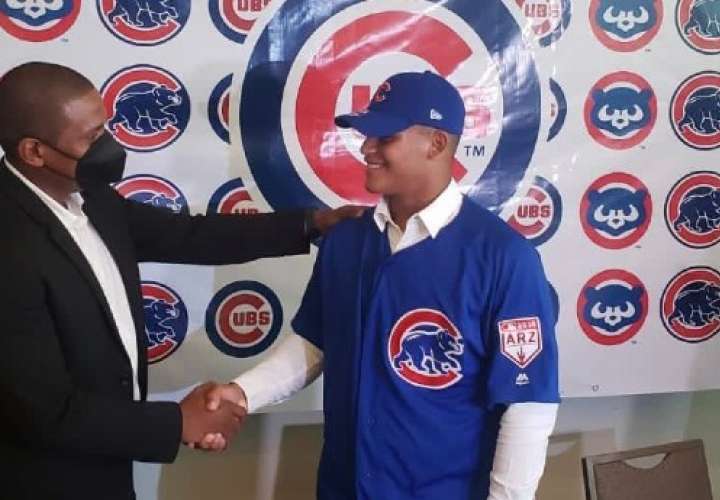 Adán Sánchez (der.) firma con los Cachorros de Chicago.