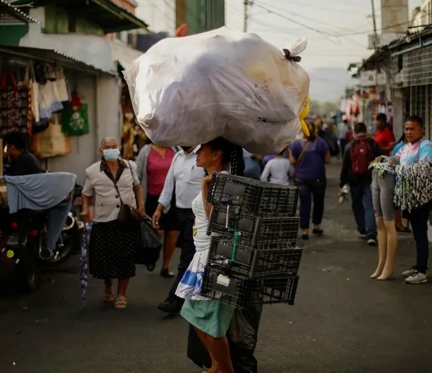 Una vendedora carga su mercadería rumbo a un puesto de venta en un mercado de San Salvador (El Salvador). Foto: EFE