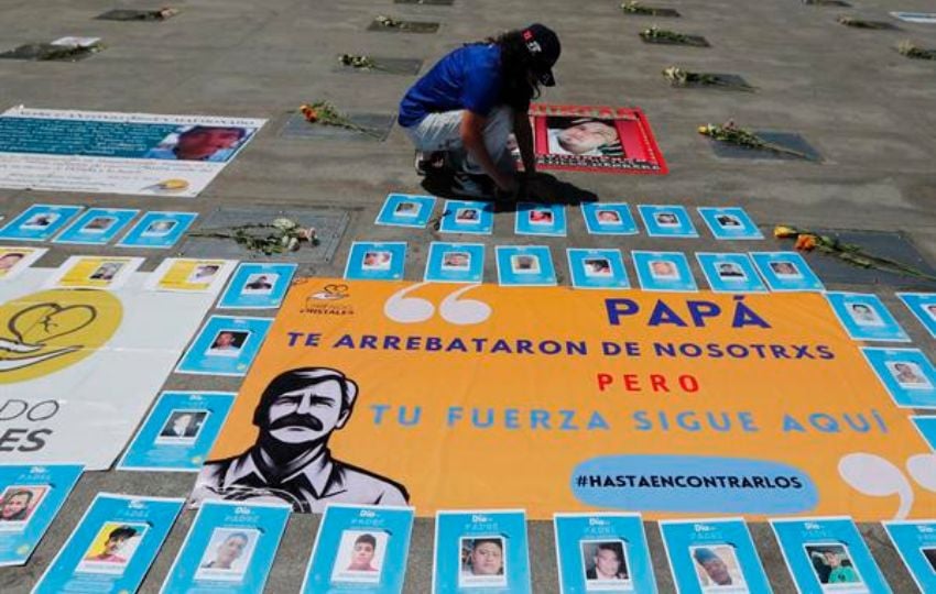 Una mujer coloca flores en memoria de los padres desaparecidos, en la Estela de Luz de la Ciudad de México. Foto: EFE