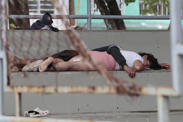 Migrantes duermen en las gradas de un coliseo.