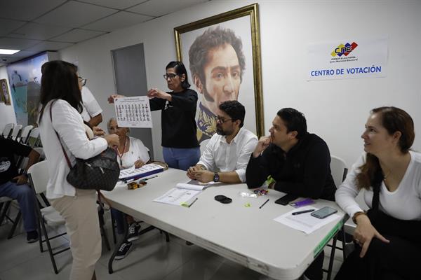 Una ciudadana venezolana recibe una tarjeta electoral para votar en las elecciones presidenciales de Venezuela este domingo, en el consulado de Venezuela en Ciudad de Panamá (Panamá). EFE