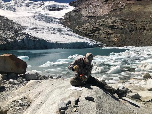 Un investigador recoge una muestra de lecho rocoso del glaciar Queshque, en los Andes peruanos. Foto: EFE