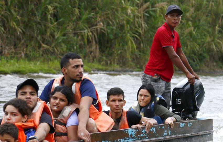 Migrantes se transportan en una lancha por el río Turquesa. Foto: EFE