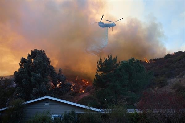 Un helicóptero arroja agua sobre una casa durante el incendio forestal de Palisades en Los Ángeles, California (EE.UU.). EFE