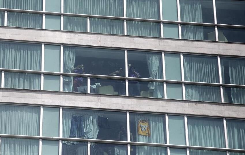 Migrantes hacen señas desde una ventana del hotel Decápolis este martes en Ciudad de Panamá, donde se mantienen tras ser deportados de EE.UU. Foto: EFE