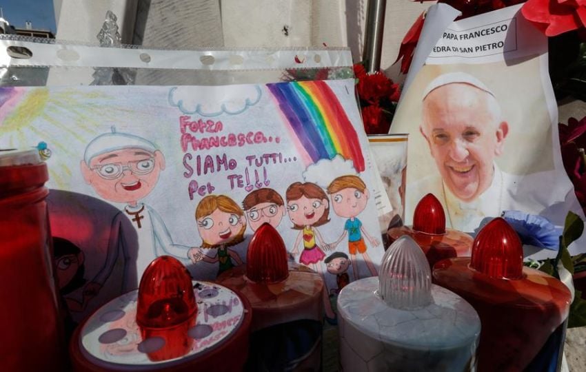 Un dibujo y una fotografía del papa Francisco bajo la estatua de Juan Pablo II. Foto: EFE