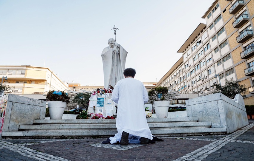 Una persona reza cerca de la estatua de Juan Pablo II frente al Hospital Agostino Gemelli, donde el Papa Francisco continúa su tratamiento. Foto: EFE