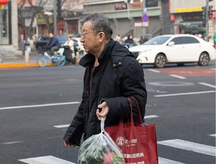 Una persona con bolsas de la compra camina por una calle transitada en Pekín, China. EFE/EPA/Jessica Lee