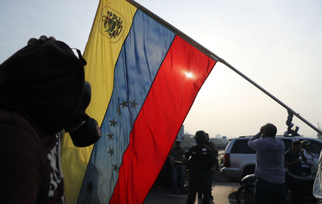 Simpatizantes del presidente interino Juan Guaidó se protegen de las bombas lacrimógenas que las fuerzas de seguridad leales al Gobierno de Nicolás Maduro. Foto/EFE